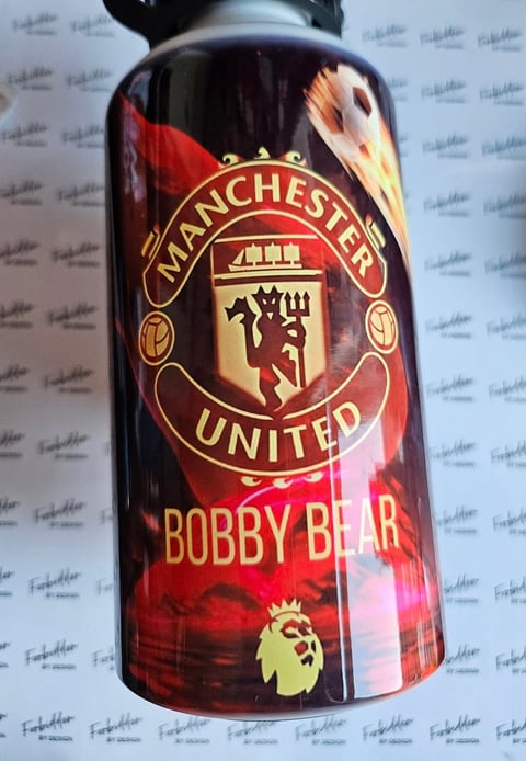 Manchester United Bobby Bear beer bottle with red label and club crest on white background